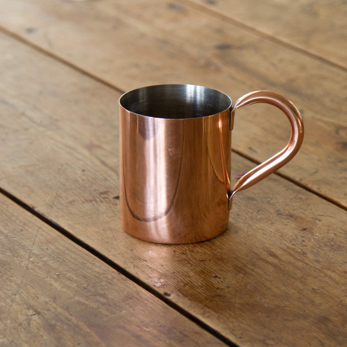 a copper mug on a wooden surface