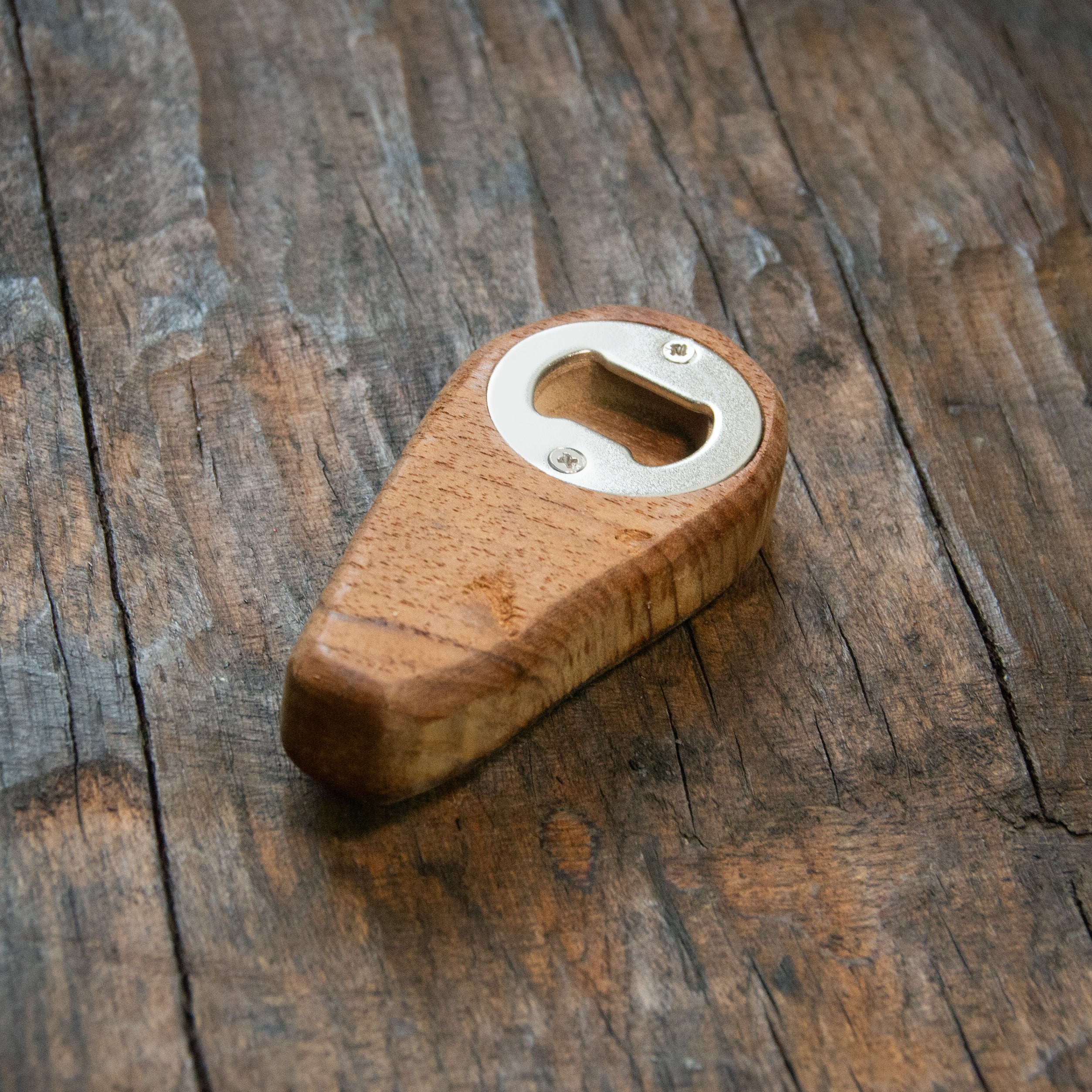 A wooden bottle opener, with a metal disc screwed in place.