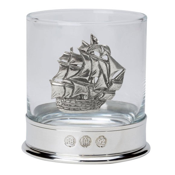 Glass tumbler with a silver ship emblem on a white background