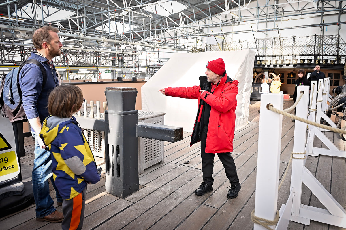 Two adults and a child interacting on the upper deck of HMS Victory