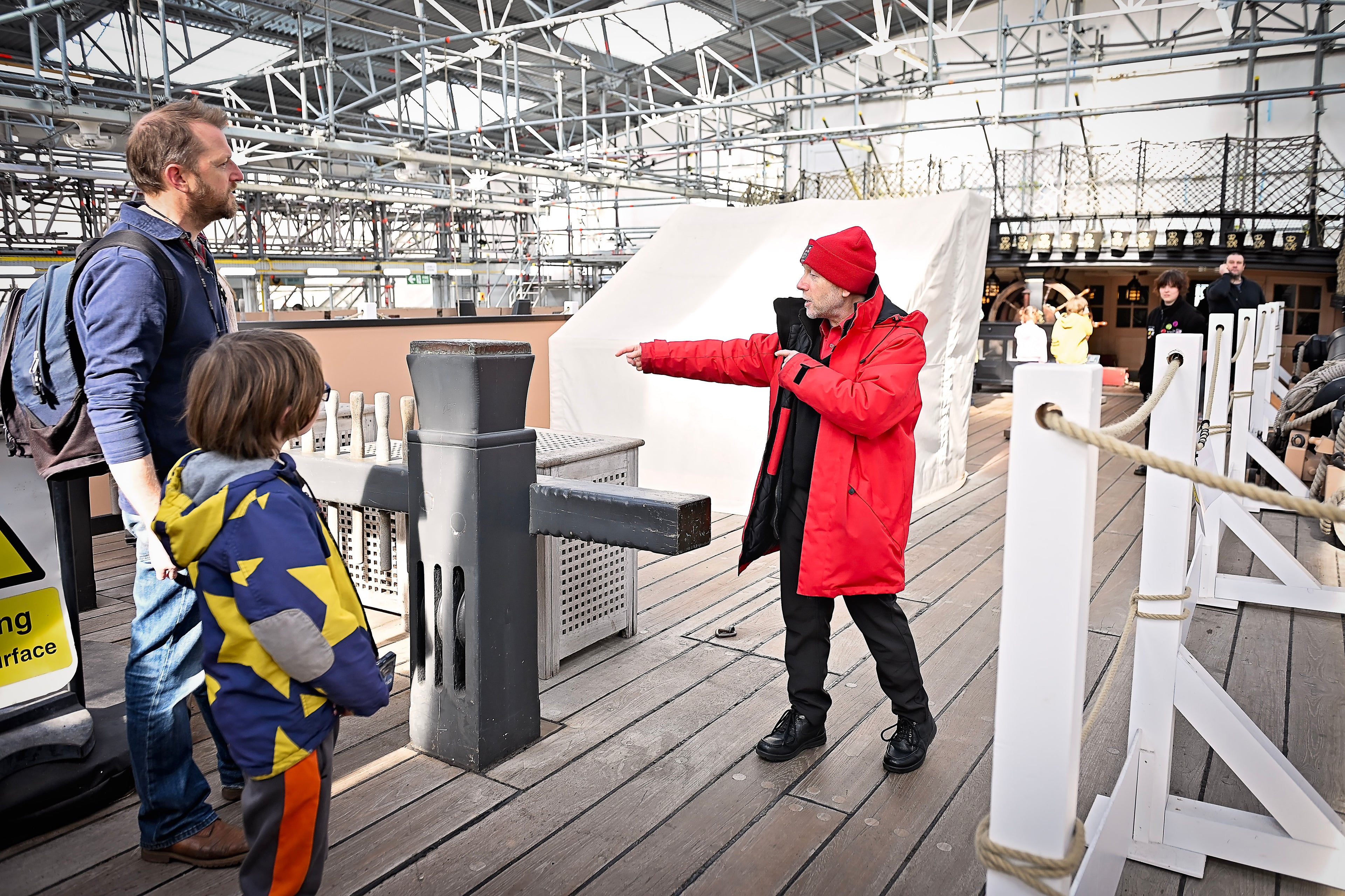 Two adults and a child interacting on the upper deck of HMS Victory