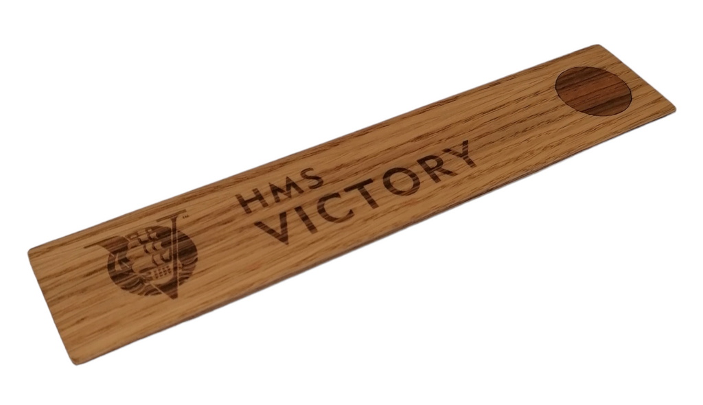 A flat piece of wood featuring timber removed during the restoration of HMS Victory, once part of the ship herself. It has the words HMS Victory marked on it.