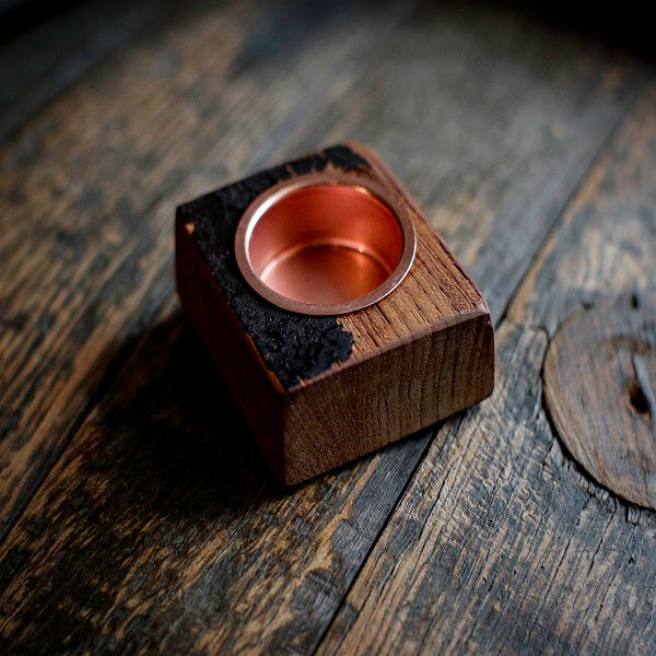 Copper candle holder on a wooden base on a rustic wooden surface