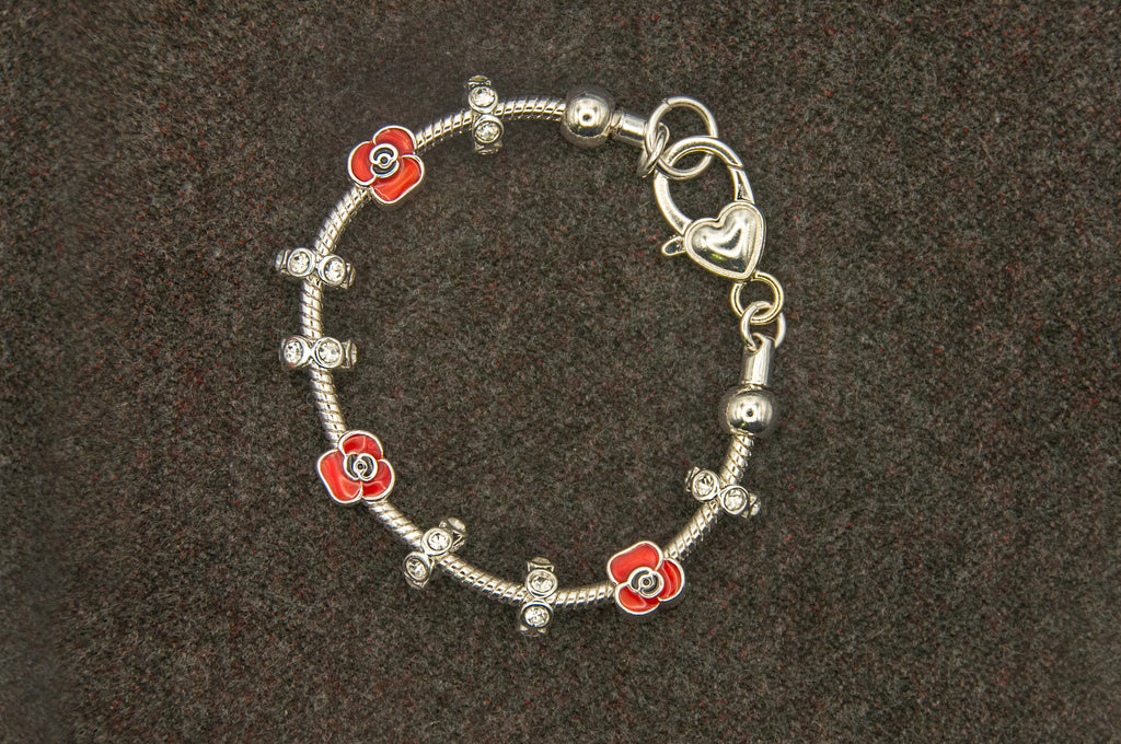 Silver bracelet with red flower-shaped charms on a dark background