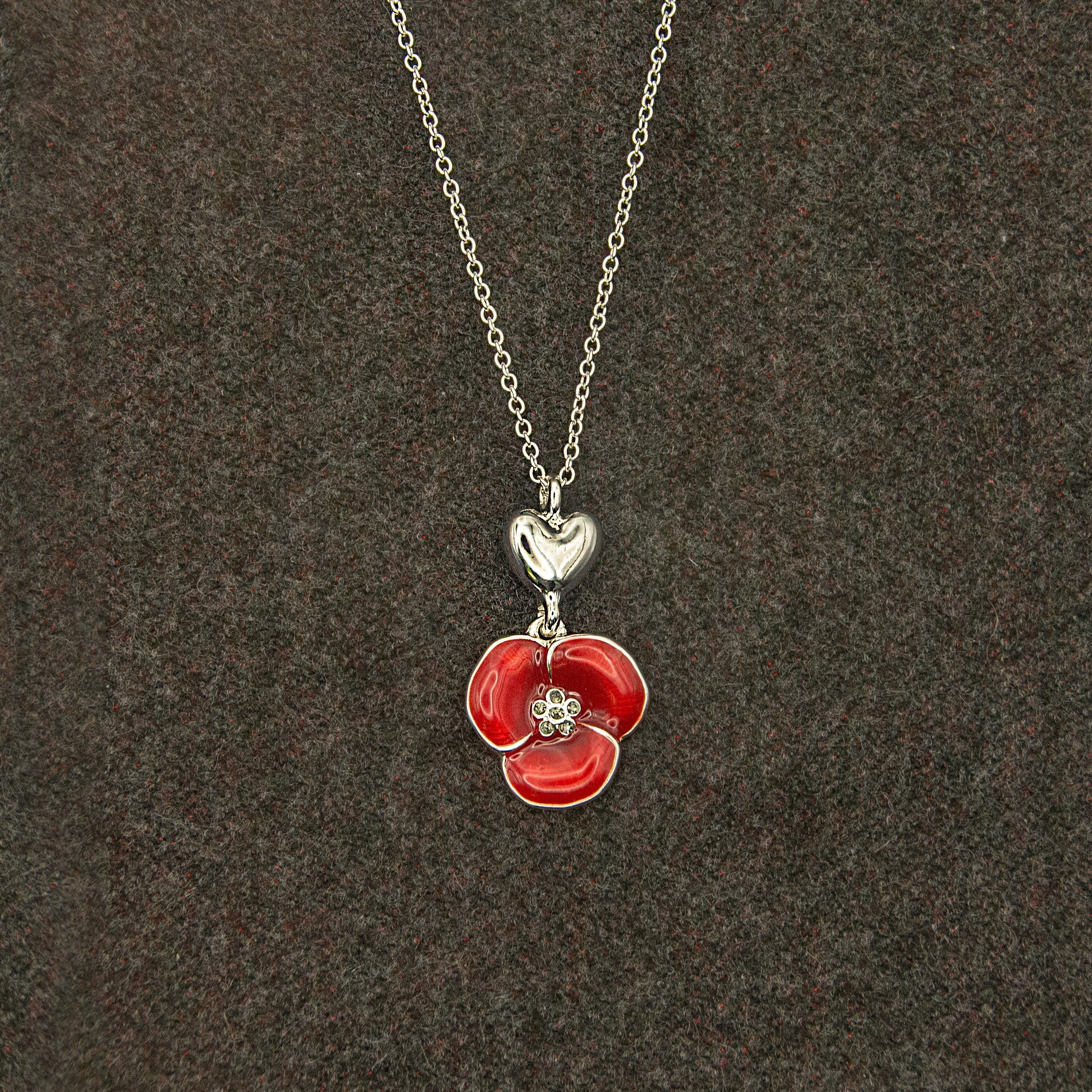 Necklace with a silver heart and red poppy flower pendant.
