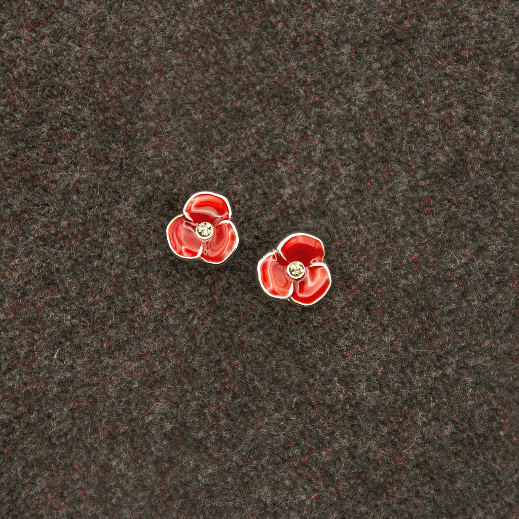 Red flower-shaped earrings on a dark textured surface