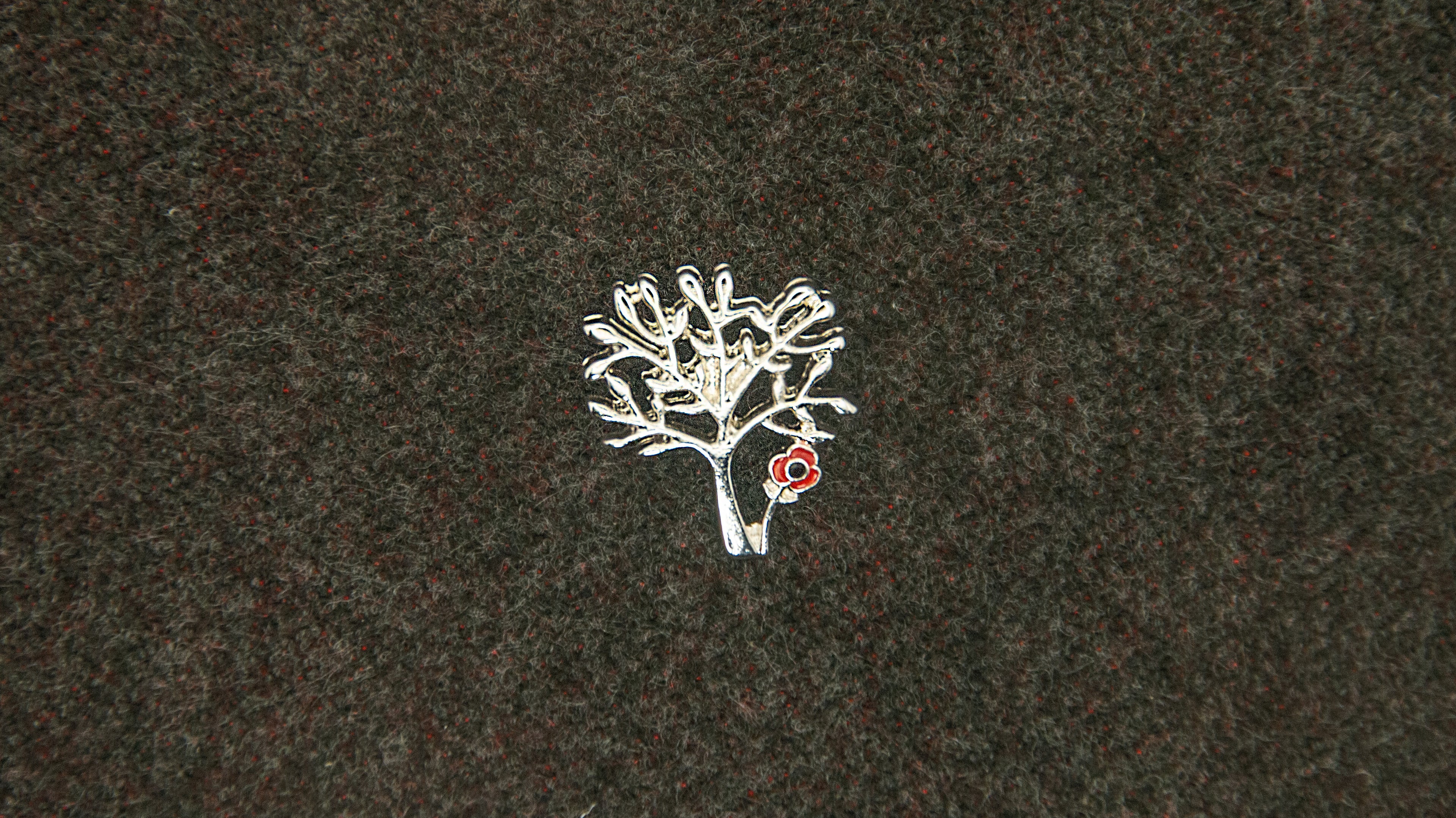 silver tree design with a small red poppy