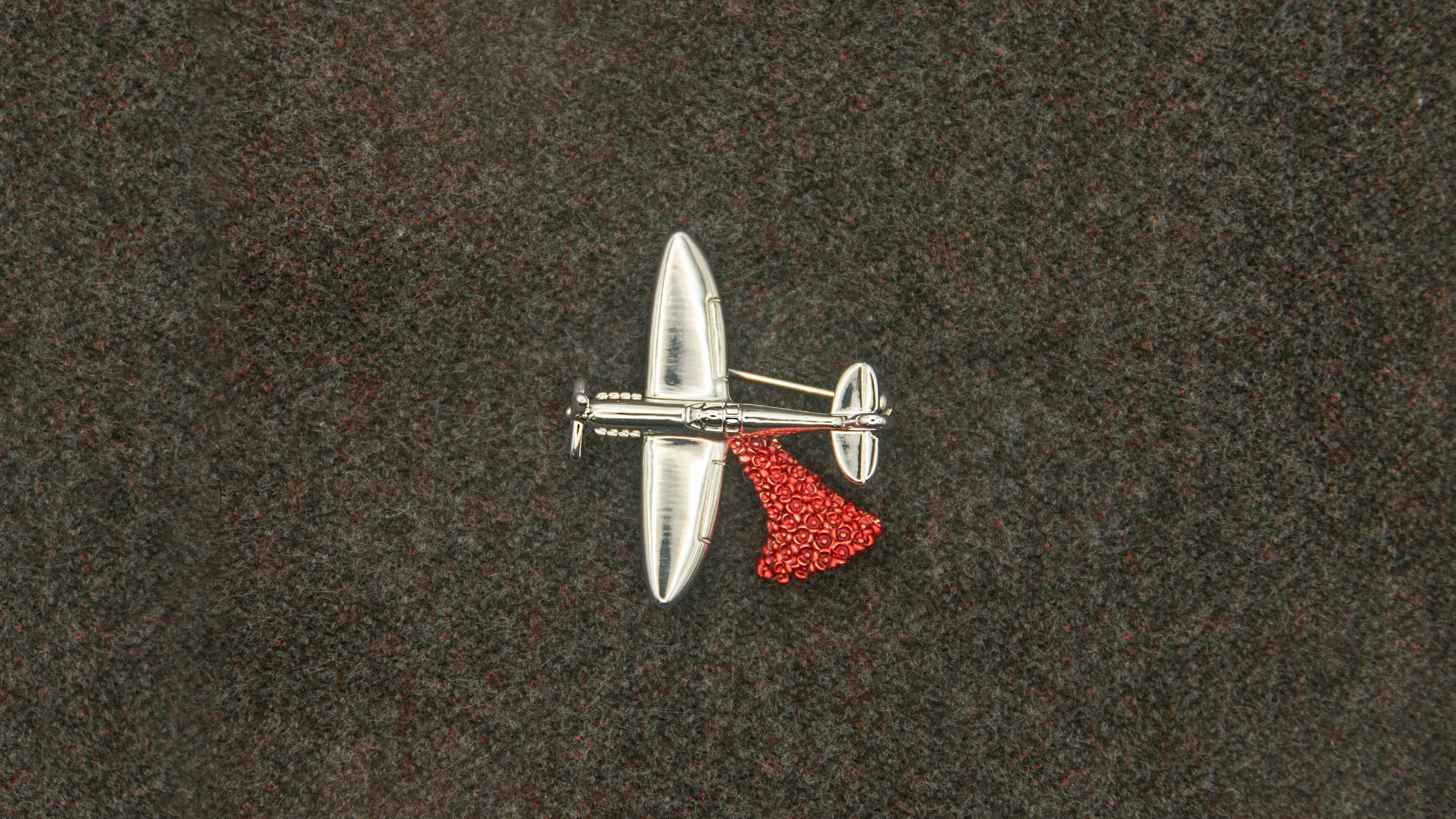 Metallic spitfire aircraft performing a 'drop' of poppies.

