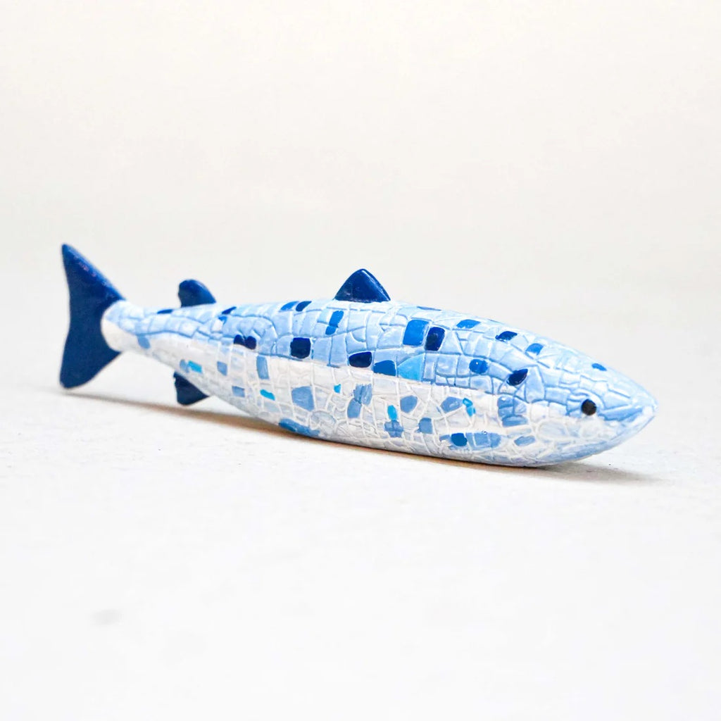 Blue and white fish-shaped ornament on a light grey background
