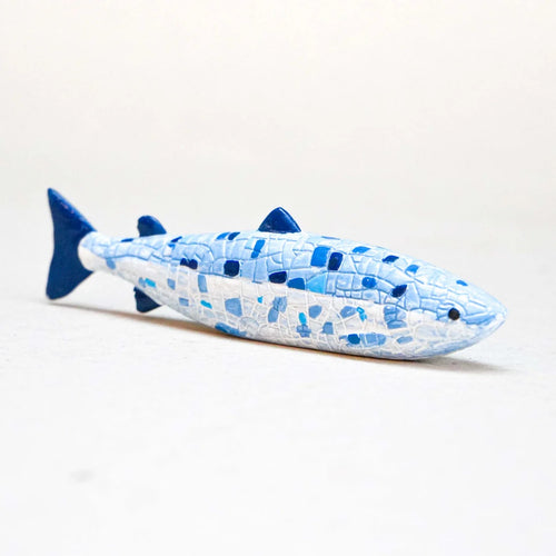 Blue and white fish-shaped ornament on a light grey background
