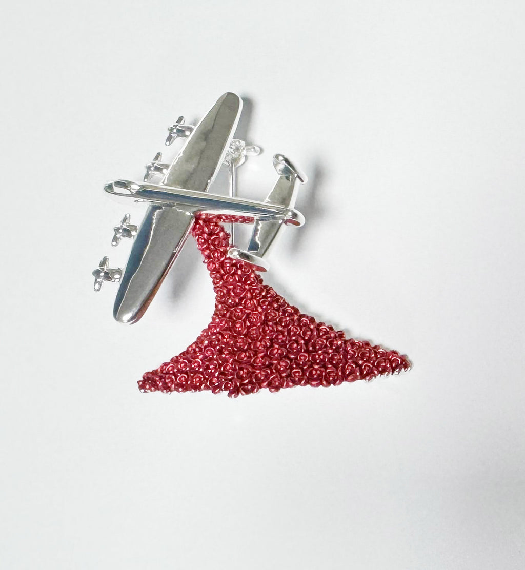 Metal Lancaster Bomber performing a “Drop” of cascading red poppies on a white background