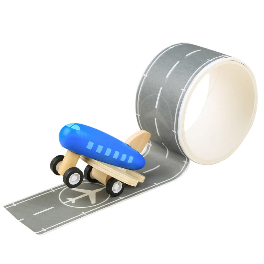 Wooden toy airplane on a roll of  runway tape with a white background